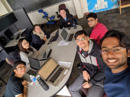 a group of students with laptop computers smiling at camera