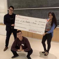 three students holding large check