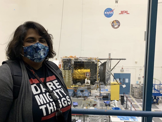 Richa at work in front of a window with astronaut equipment
