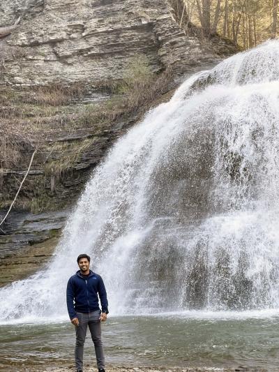 Manoj standing in front of a large waterfall.