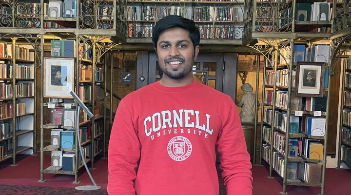 Manoj in library with a red Cornell sweatshirt on.