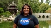 Richa Sirohi with a NASA t-shirt standing in front of a pagoda like structure and pond.