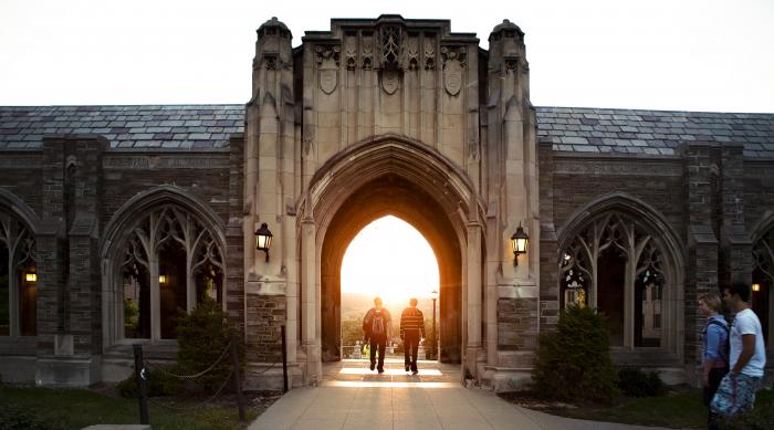 two students walking on Cornell campus into the sunset